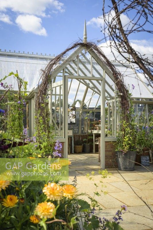 Alitex National Trust Collection Greenhouse in Wood Sage, entrance framed by Sweet Peas in large pots and Calendula - marigold flowers at RHS Hampton Court Palace Garden Festival 2022 