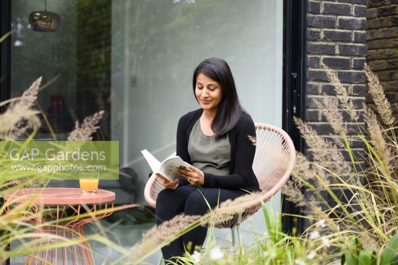 Meera, the owner reading a book in the garden. 
