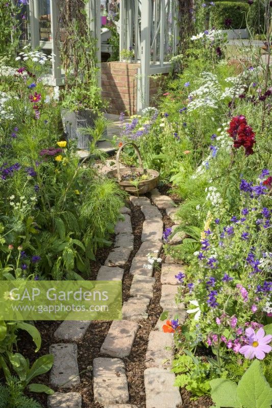 Reclaimed brick and wood chip path by a flower border in Alitex cutting garden at  RHS Hampton Court Palace Garden Festival 2022  