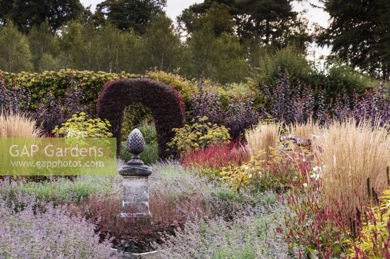 Pine cone finial surrounded by Nepeta 'Six Hills Giant', Persicaria amplexicaulis 'Dark Red' and Calamagrostis x acutiflora 'Karl Foerster' at Whitburgh House Walled Garden in September.