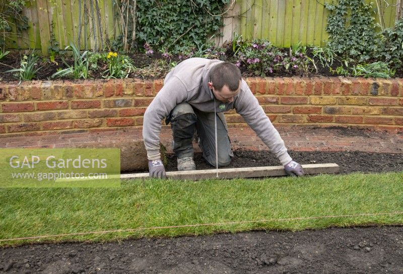 A worker laying new turf during the makeover of a London garden.