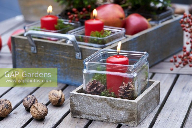 Table arrangement of a red candle in a wooden box and surrounded by wallnuts and candles