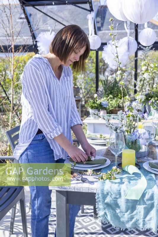 Woman laying table decorations in greenhouse
