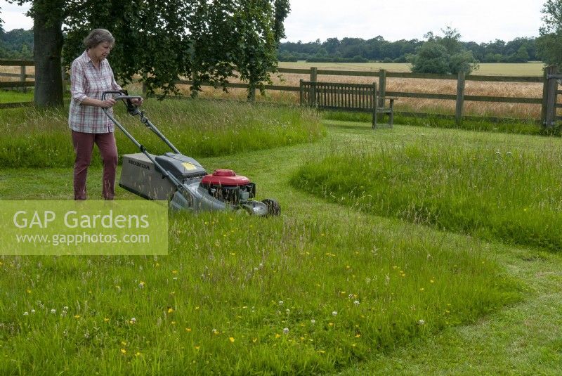 Woman mowing paddock leaving areas for wildlife and wildflowers to flourish