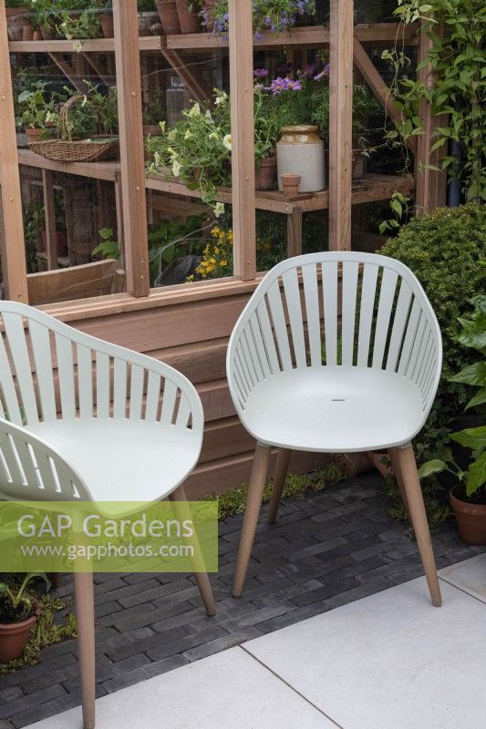 Two garden chairs sitting on paving in front of a cedar greenhouse.

The Gabriel Ash showstand at RHS Chelsea Flower Show 2023.