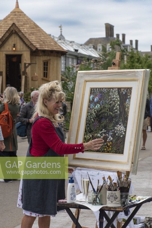 Artist Sherree Valentine Daines paints a picture beside The Royal Entomological Garden. Chelsea Flower Show 2023.