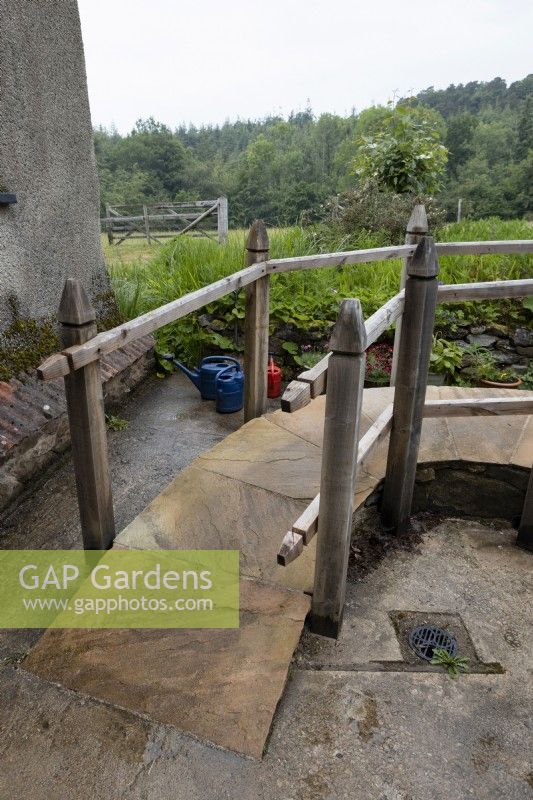 A paved, curving wheelchair ramp with rustic handrails. Summer. June. 