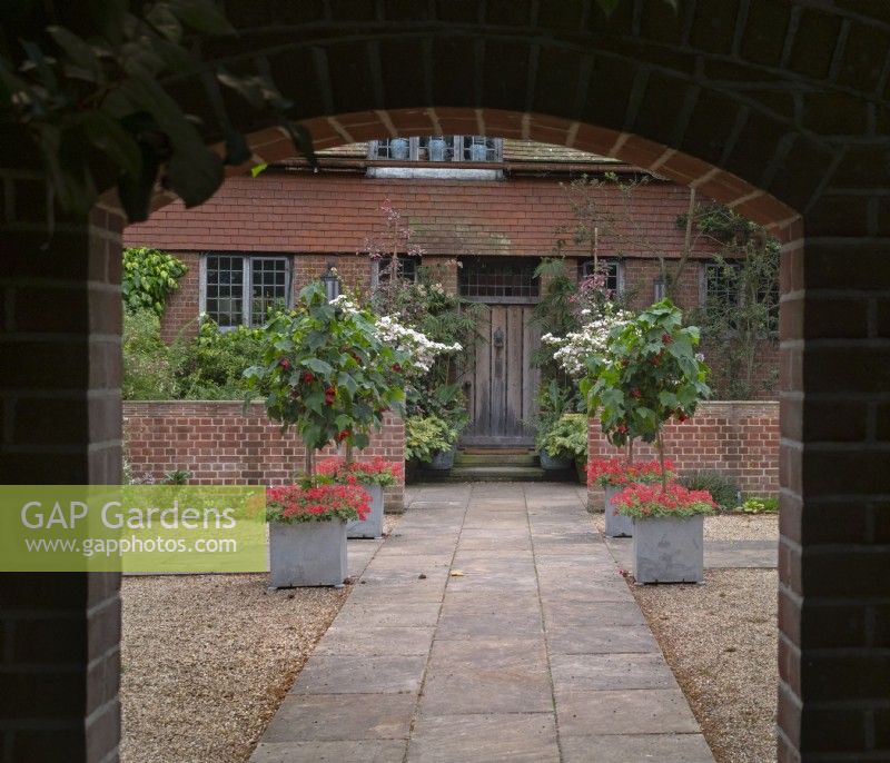  Entrance Court at East Ruston Old Vicarage Gardens, Norfolk July Summer.  Formal arrangement of square planters at intersection of paved paths 
