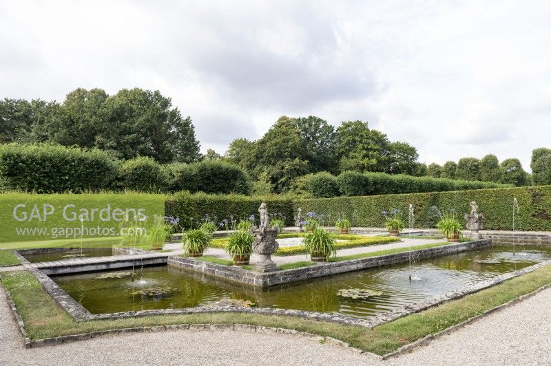 Hannover Germany Herrenhausen Royal Gardens. Inselgarten. Island Garden. Featuring statues, a water feature with an island and agapanthus in pots. 