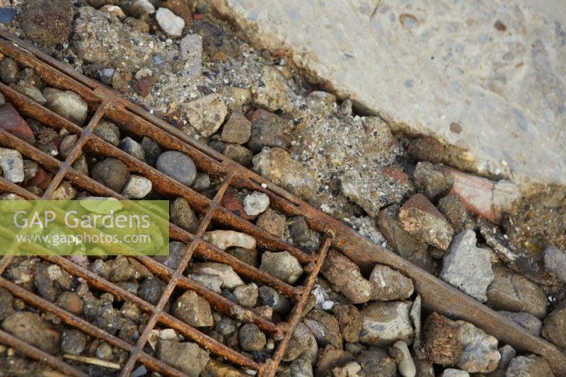 Detail of garden path using stones and rusty metal grid. Summer.