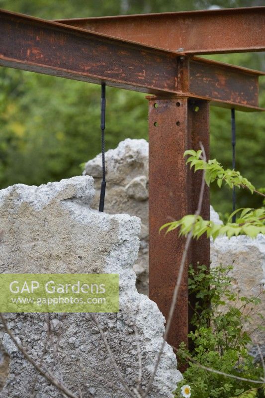 The Samaritans Listening Garden. Designer: Darren Hawkes. Chelsea Flower Show 2023. A garden of salvaged materials and suspended concrete panels. Rusted metal structure. Summer. May.