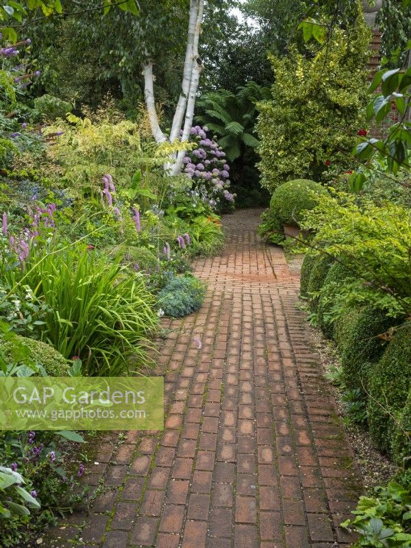 Brick pathway and borders with Sanguisorba hakusanensis 'Lilac Squirrel'