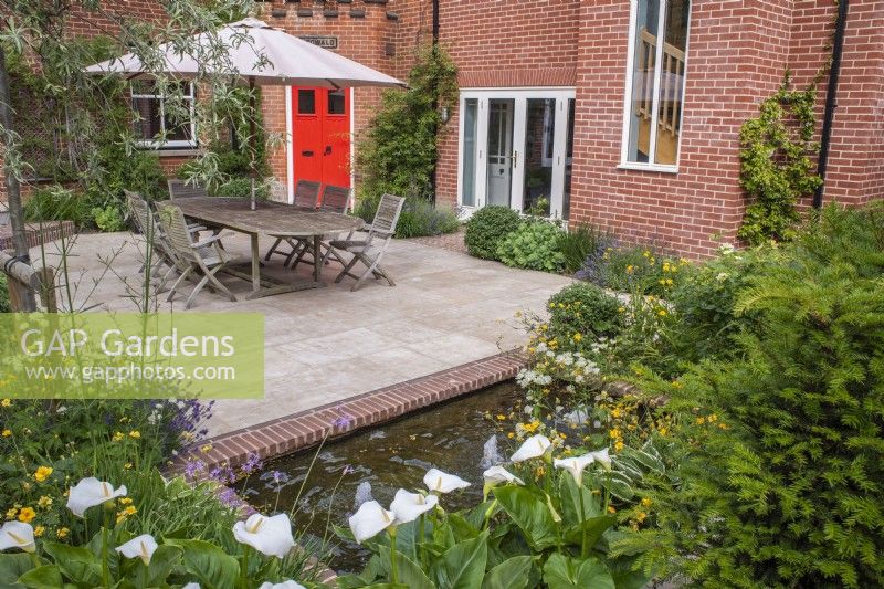 Courtyard garden with sandstone paving, garden furniture and a brick edged small water feature with bubble fountains 