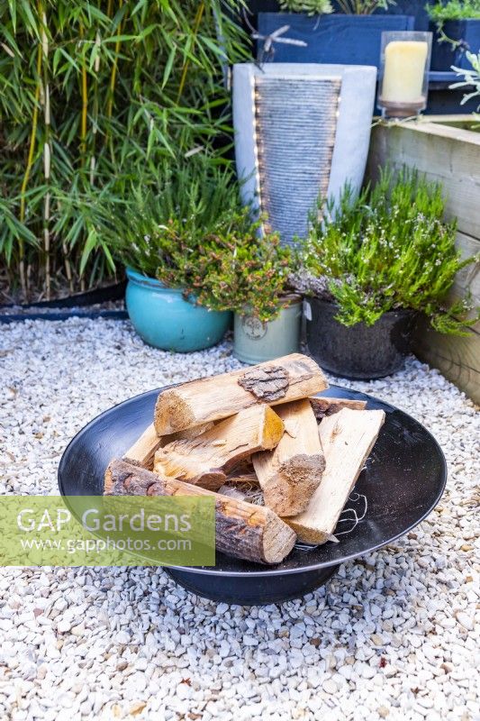 Firepit in gravel garden with small water feature behind