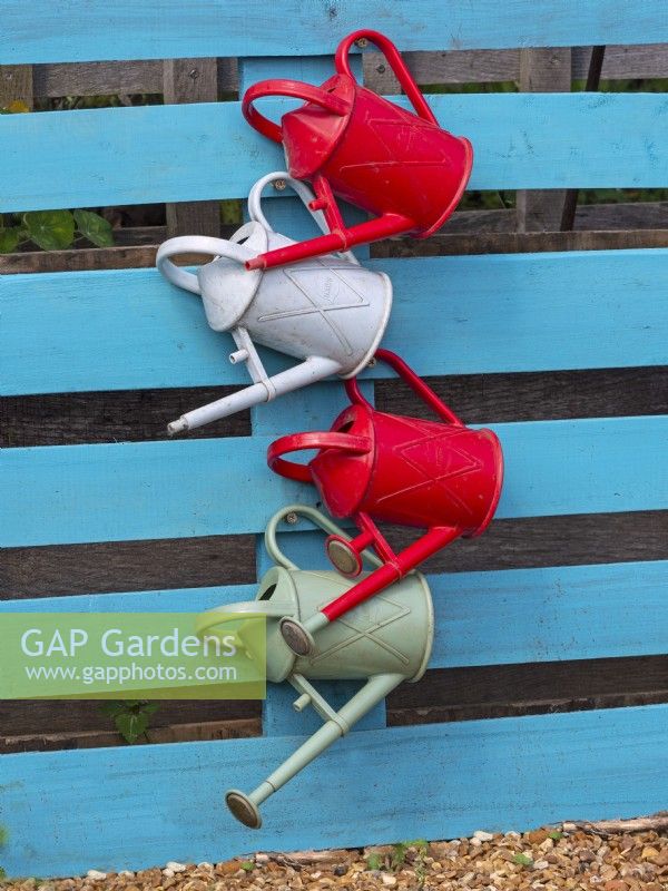 Watering cans hung up at different heights in a school garden, August Summer