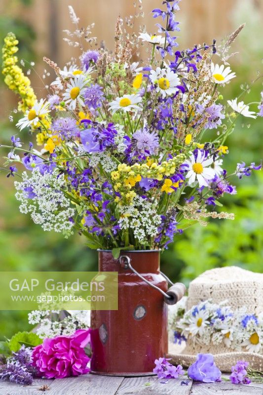 Wild flower bouquet in milk churn containing daisies, wild carrots, field scabious, meadow clary and verbascum.