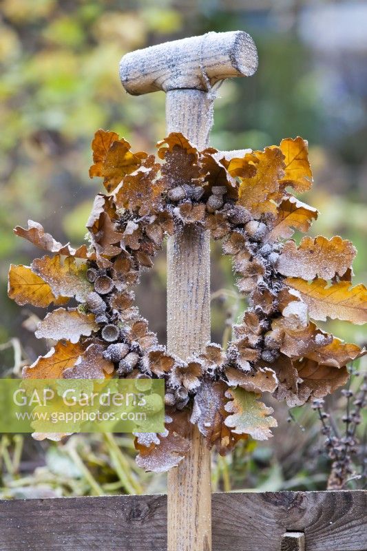 Leaf and acorn wreath hanging from garden fork handle.