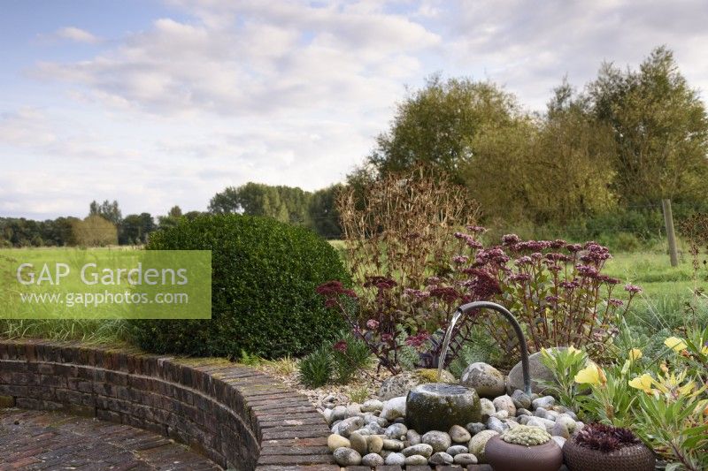 Water feature on a raised bed in a country garden in September