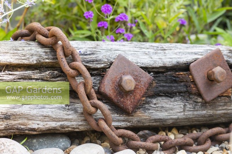 Driftwood with rusted chain and pebbles on gravel