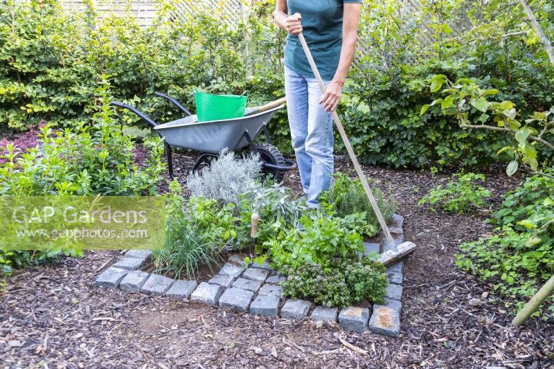 Woman sweeping compost off the surface of the granite setts