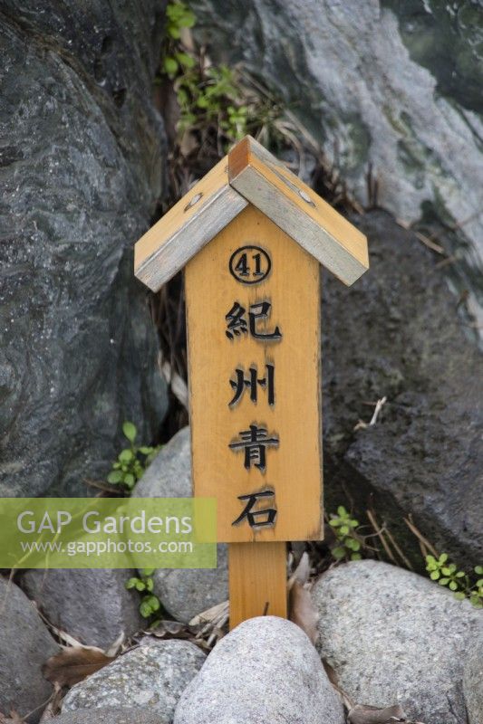 Wooden post with inscription in Japanese next to one of the placed stones.