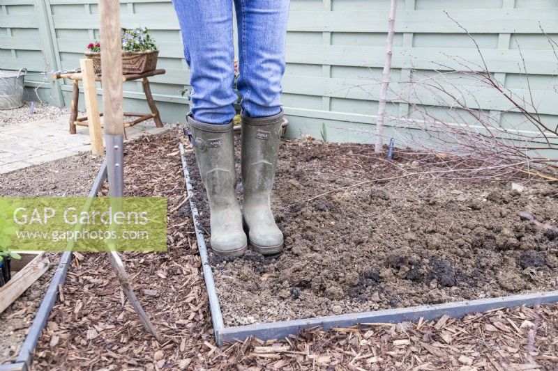 Woman stepping on compost to firm it in