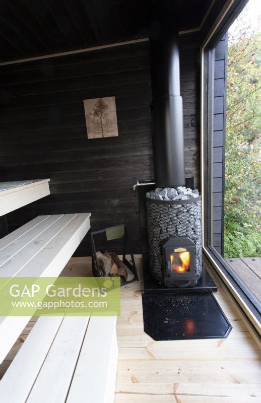 Timber black painted wood sauna cabin with a glass window view to the garden