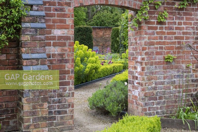 A doorway in the kitchen garden wall frames the view of the formal parterre beyond.