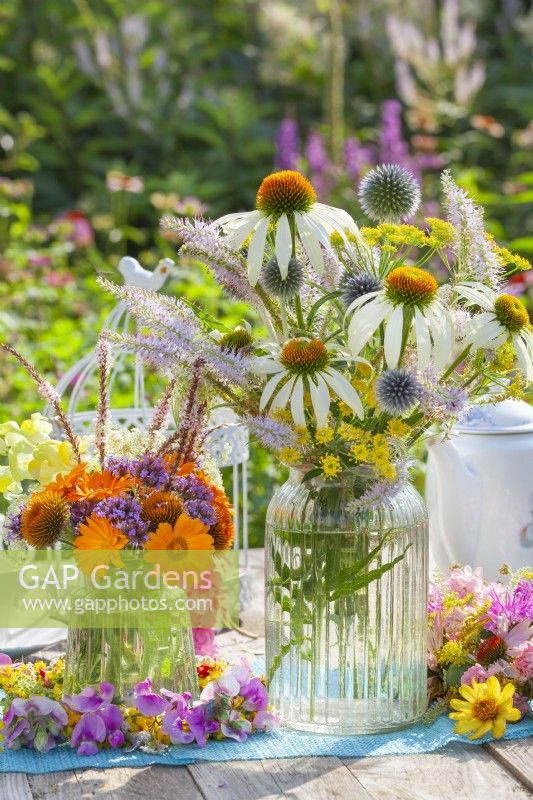Floral arrangement in glass vases including pot marigold, echinops, fennel, verbena, persicaria and white coneflowers