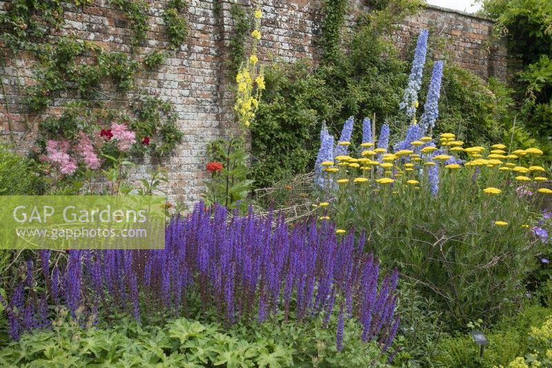 Mixed border against a brick wall at Waterperry Gardens, July