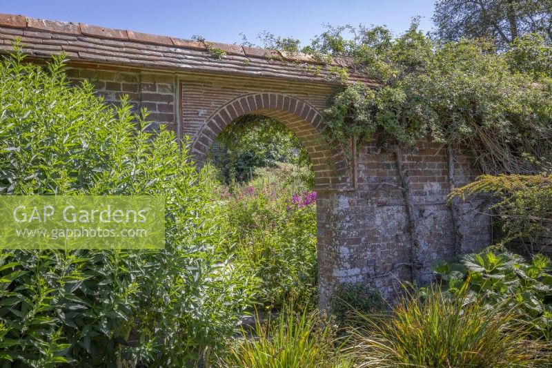 Looking towards the arch from the Mosaic Garden into the Barn Garden at Great Dixter