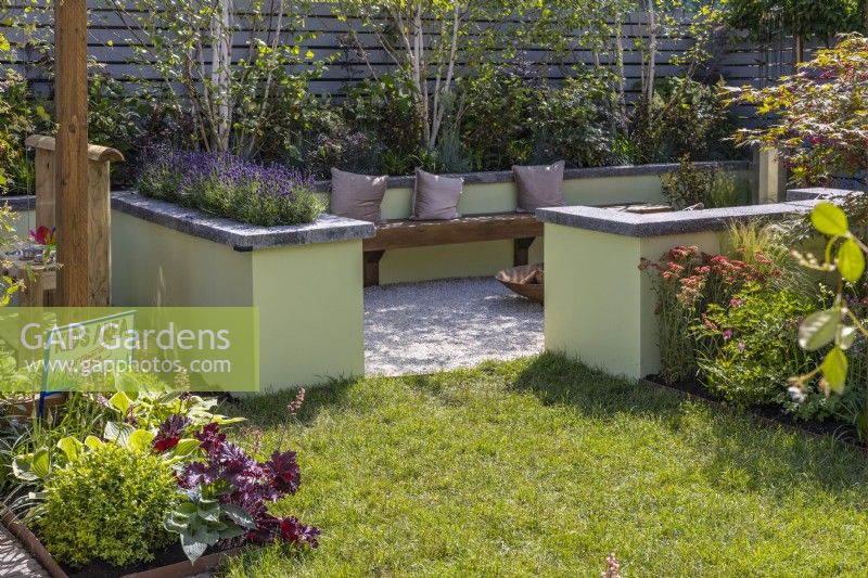 Small modern garden with colourful perennial beds, kid's area, lawn and relaxation spot. The raised border bed planted with Betula utilis jacquemontii 'Multi Stem', Sambucus nigra 'Black lace,' Festuca glauca 'Elijah Blue' and Lavandula angustifolia 'Essence Purple'.  June.  Designer: Colm Carty, Bord Bia Bloom, Dublin 2023 