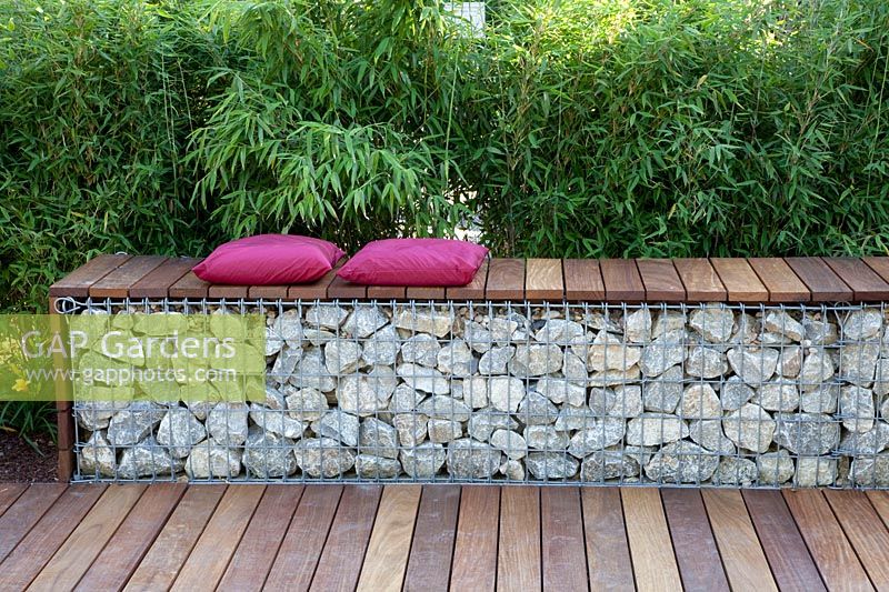 Gabion as a seating area in front of a bamboo hedge 