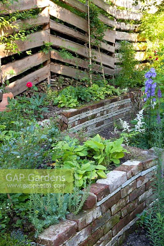 Plant beds made of old stones, fence made of bark boards 