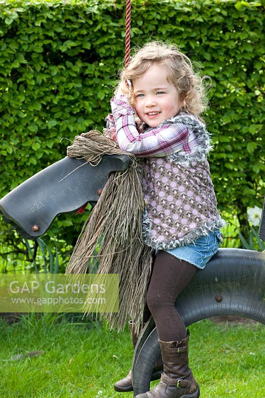 Child in the garden on a toy horse 