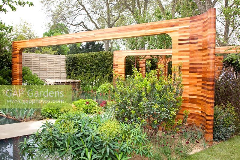 Ornamental wooden arches made of Red Cedar in the garden, Prunus maackii Amber Beauty, Euphorbia, Iris germanica Bronze, Libertia grandiflora, Pittosporum tobira Nanum 