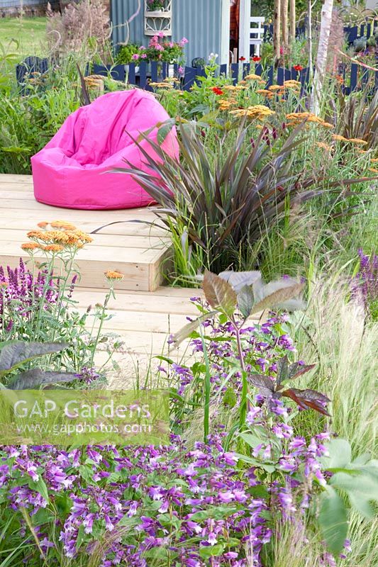 Modern garden with wooden deck, Achillea Terracotta, Phormiunm tenax 