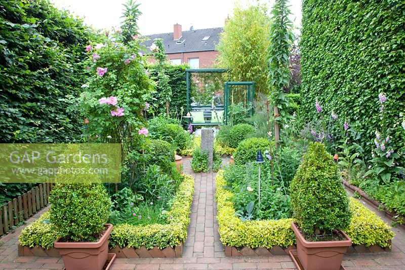 Small cottage garden with creeping spindle as bed edging, Euonymus fortunei 