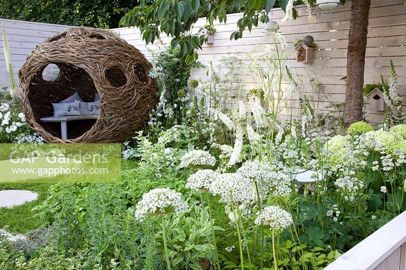 Willow arbor and flower bed in white with birdhouses on the fence, Hosta Fire and Ice, Digitalis purpurea, Campanula persicifolia Alba, Hydrangea 