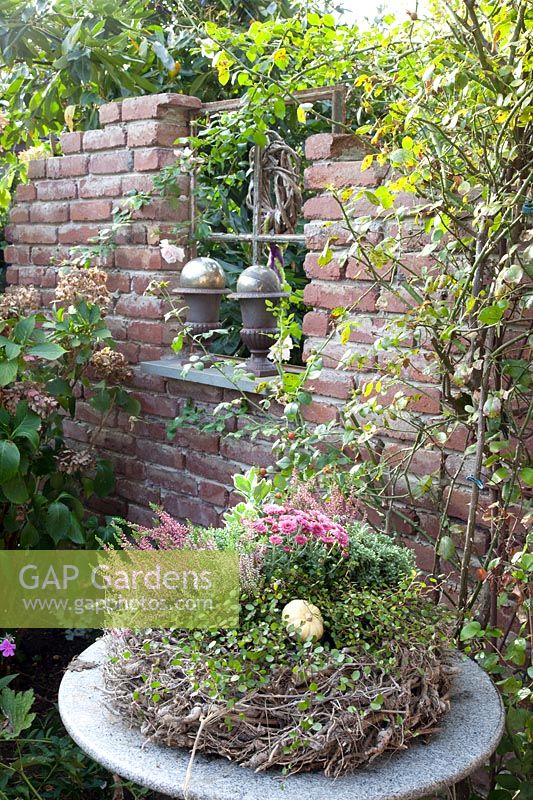 Ruined wall in the garden and autumn wreath on a table 