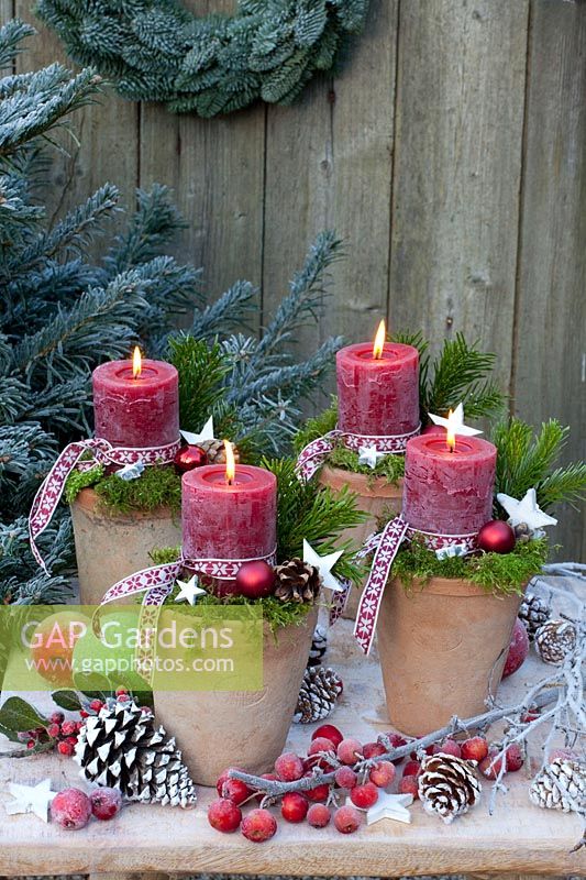 Candles in pots, decorated with moss and ribbon 