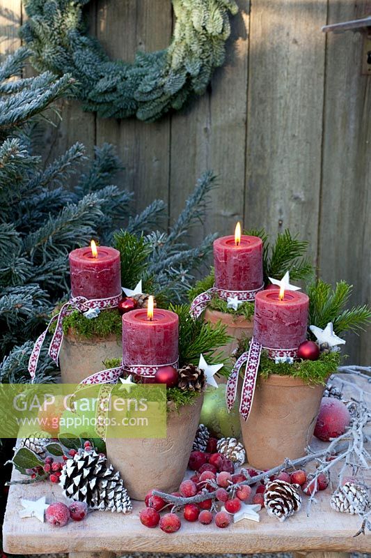 Candles in pots, decorated with moss and ribbon 