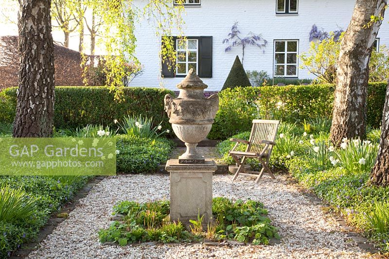 Formal garden area with vase in the middle 