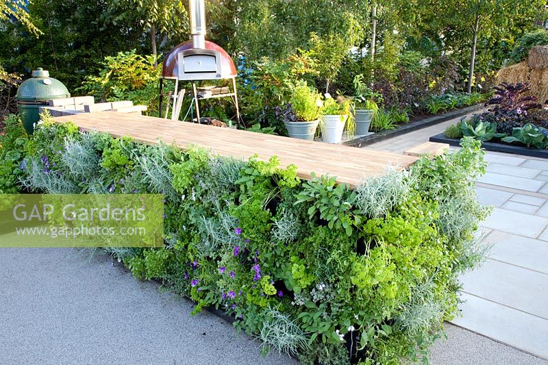 Vegetable garden with outdoor kitchen, work surface on the sides with herb bags planted vertically 