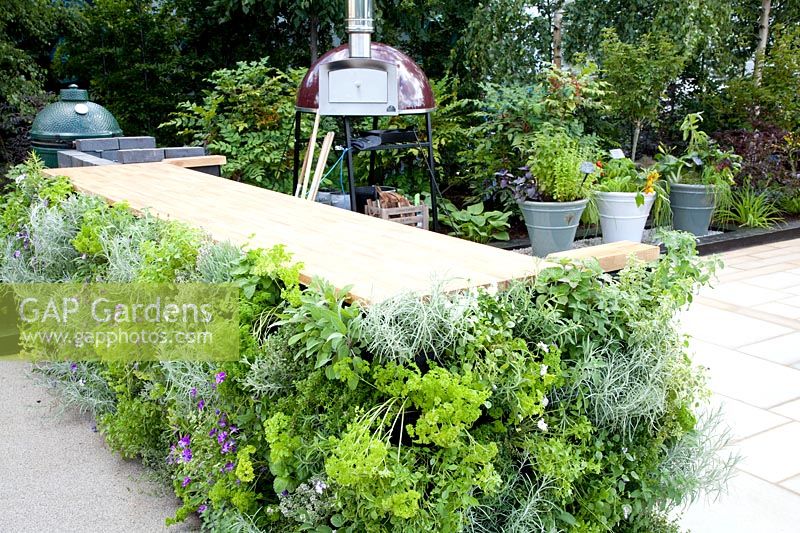 Vegetable garden with outdoor kitchen, worktop on the sides planted vertically with herbs 