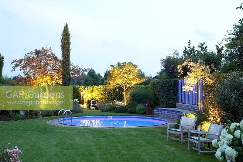 Illuminated garden with pool, crabapple and serviceberry, Malus, Amelanchier 