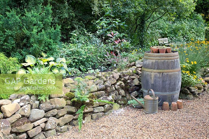 Stone wall and old wooden barrel as garden decoration 