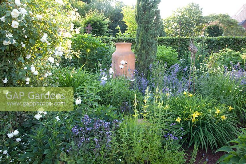 Perennial bed with roses and amphora 