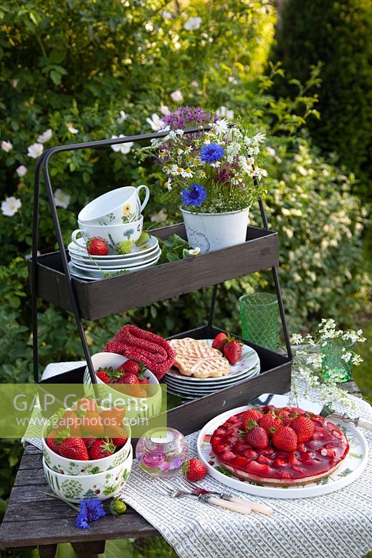 Etagere with dishes, strawberry cake and strawberries 