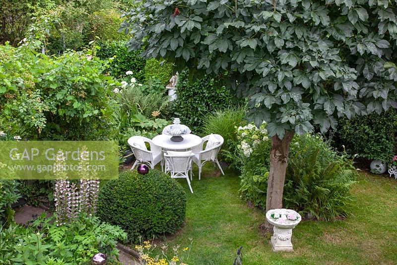 Romantic garden with chestnut tree and seating area 